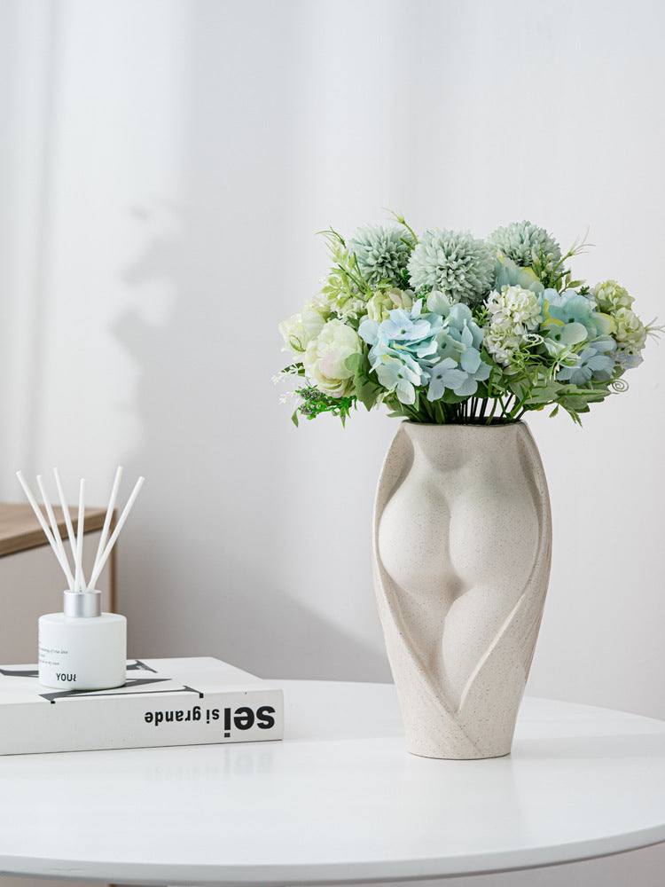 Modern ceramic flower vase with feminine silhouette, arranged with soft green and white blooms, enhancing elegant tabletop decor.