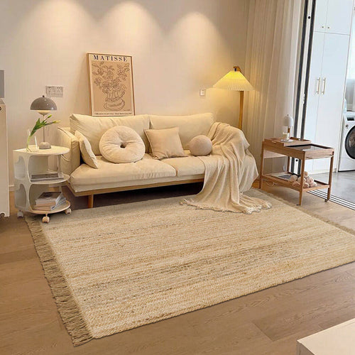 Hand-woven jute rug with fringe edges, adding a natural, rustic touch to living room or bedroom decor.