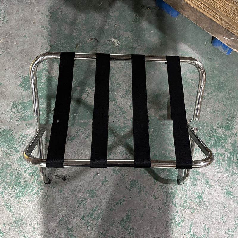 Stainless steel luggage rack placed in a hotel room, designed for holding suitcases and travel bags conveniently