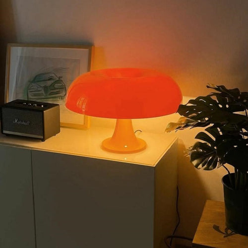 Decorative Mushroom Lamp in orange on a cabinet beside a plant, ideal for bedroom or living room ambiance with 3-color USB lighting.