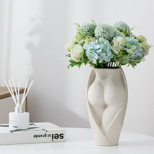 Simple modern ceramic vase with artistic female form, filled with pastel floral arrangement, ideal for minimalist home decor.