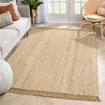 Hand-woven jute rug with fringe edges, adding a natural, rustic touch to living room or bedroom decor.