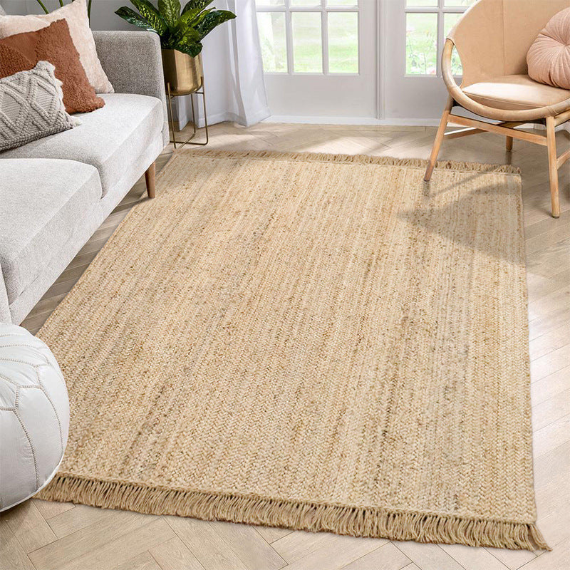Hand-woven jute rug with fringe edges, adding a natural, rustic touch to living room or bedroom decor.
