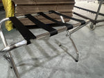 Stainless steel luggage rack placed in a hotel room, designed for holding suitcases and travel bags conveniently