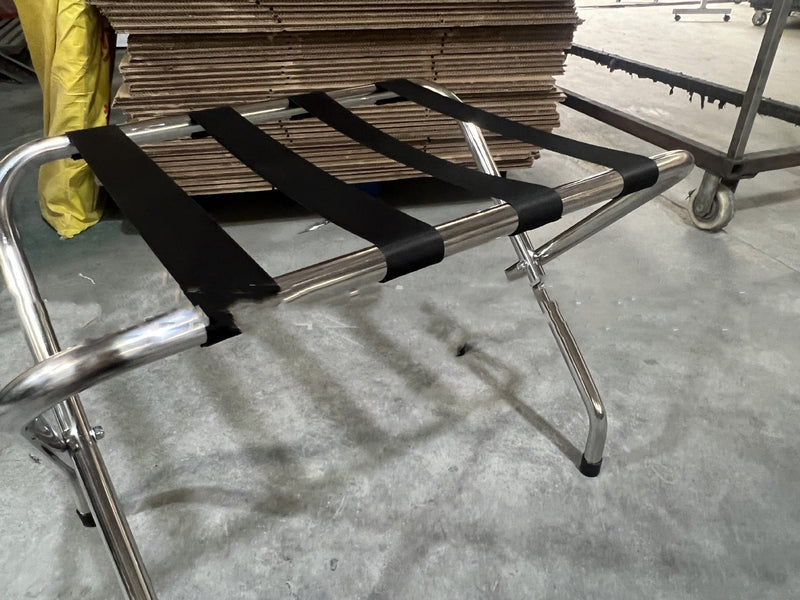 Stainless steel luggage rack placed in a hotel room, designed for holding suitcases and travel bags conveniently