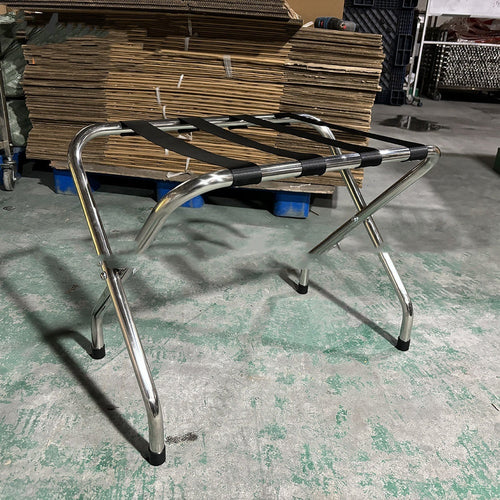 Stainless steel luggage rack placed in a hotel room, designed for holding suitcases and travel bags conveniently