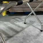 Stainless steel luggage rack placed in a hotel room, designed for holding suitcases and travel bags conveniently