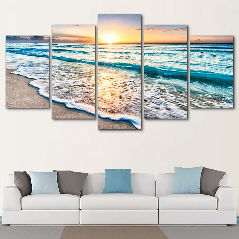 Sunset beach waves 5 panel ocean wall art displayed above a white couch with blue and gray pillows. Canvas print, frameless design.