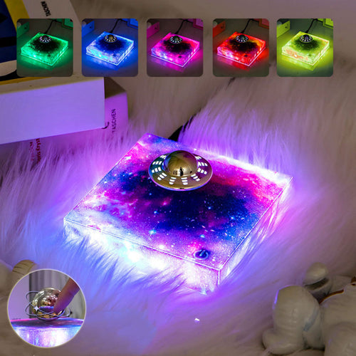 Levitating UFO Galaxy Lamp floating above its magnetic base, glowing with colorful galaxy-like light in a dark room.